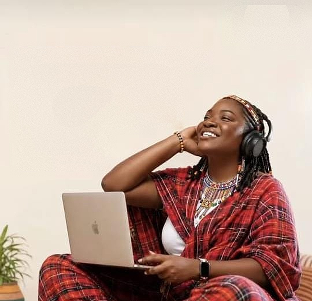 A woman smiling with headphones and a laptop